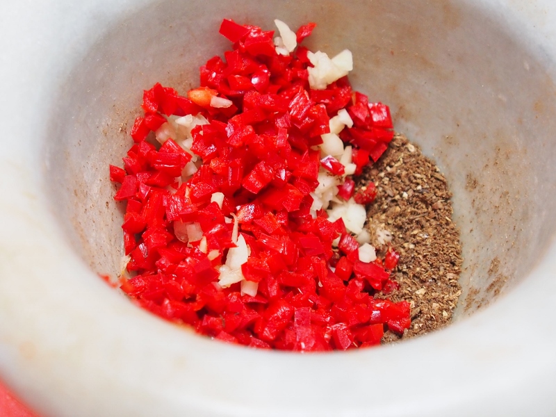 Harissa paste being made in a mortar and pestle